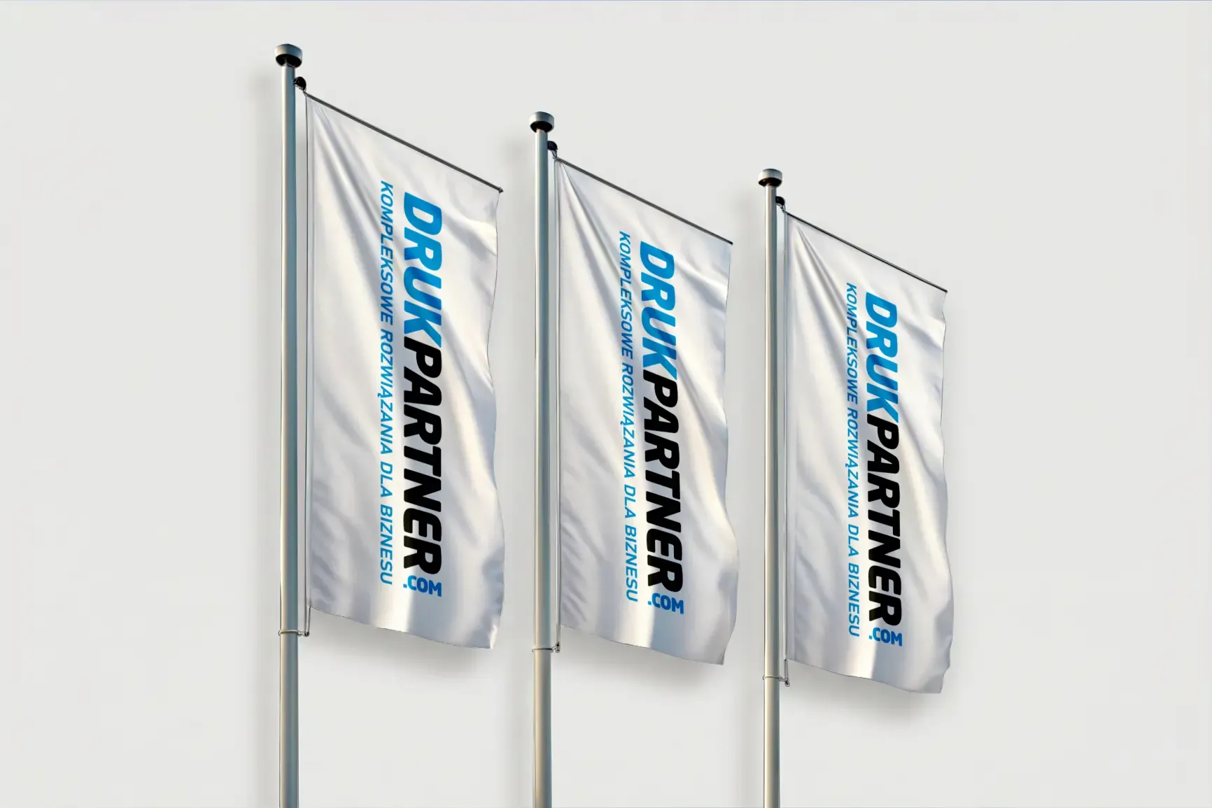 Trzy flagi reklamowe z nadrukiem Drukpartner.com zamocowane na masztach.